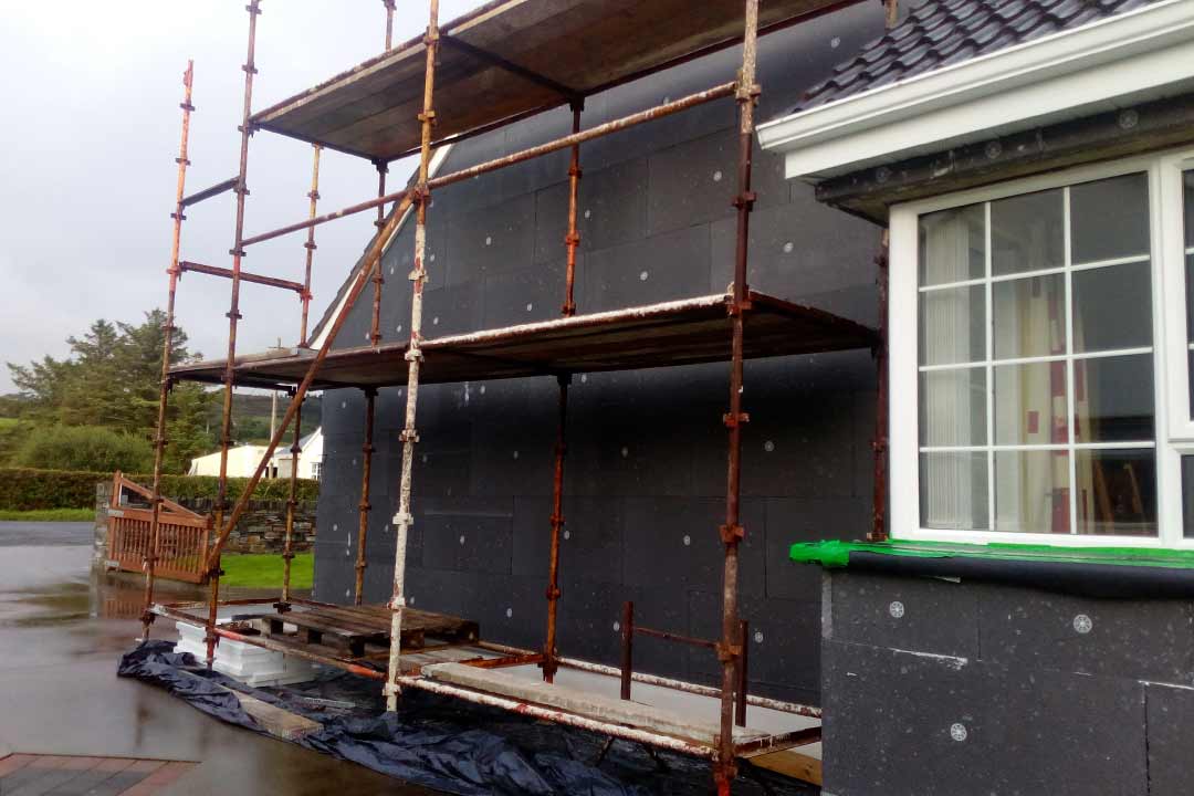 External wall insulation being fitted to the outside wall of a house